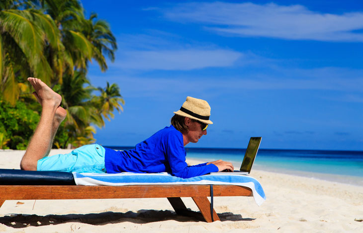 Mann mit Laptop am Strand